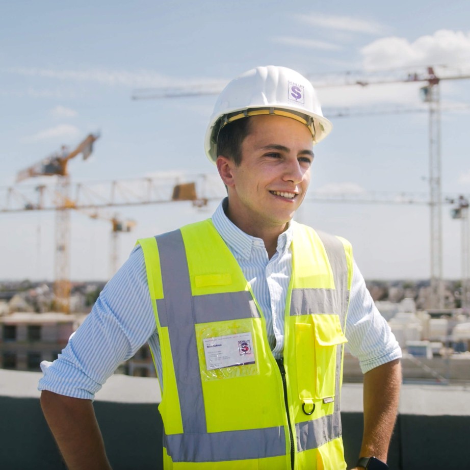 Bauleiter und Digitalisierungsmanager der Baufirma Schlun in Sicherheitsausrüstung auf der Baustelle erklärt die Bausoftware Vorteile.