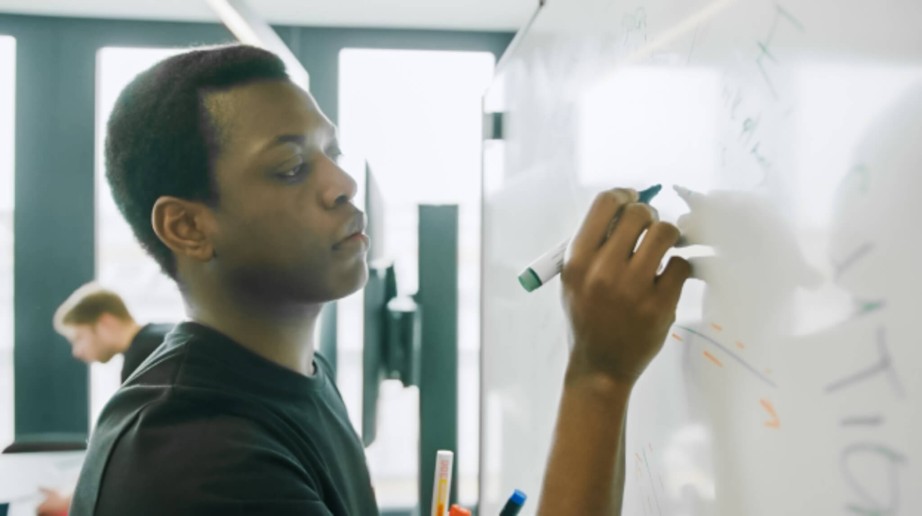 Ein Mitarbeiter von specter automation visualisiert die Vorteile der Bausoftware am Whiteboard. Er beschreibt den digitalen Baufortschritt und zeichnet die Vorteile auf.